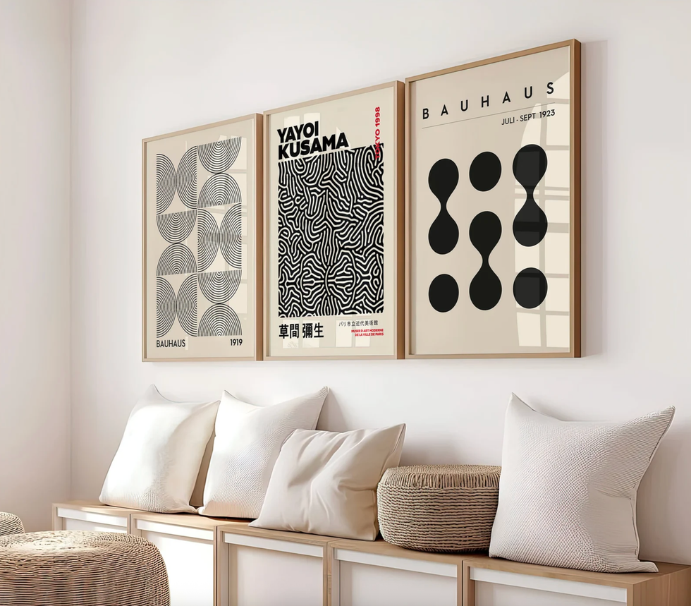 Three abstract art posters above a bench with pillows and a woven basket.