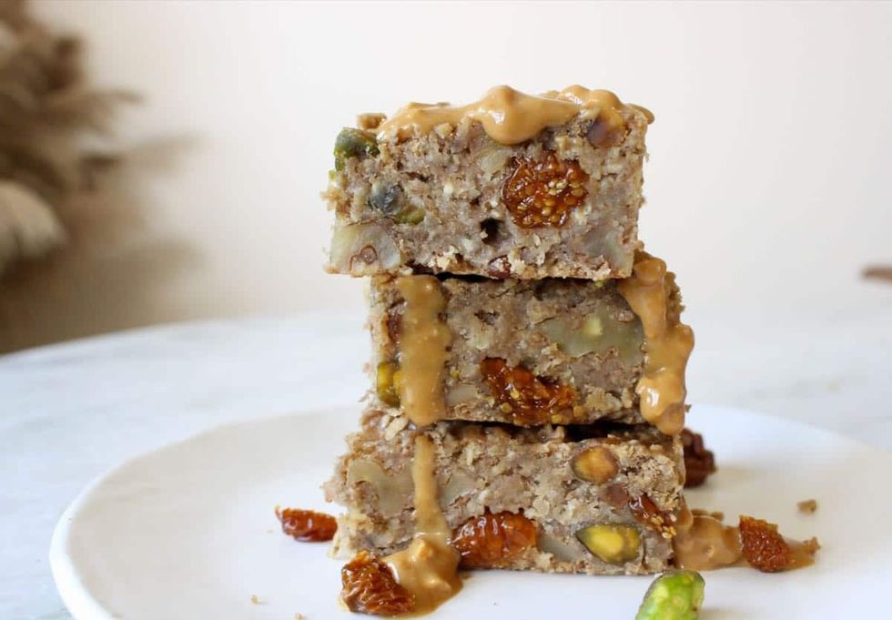 Three oatmeal breakfast bars are stacked on a white plate.
