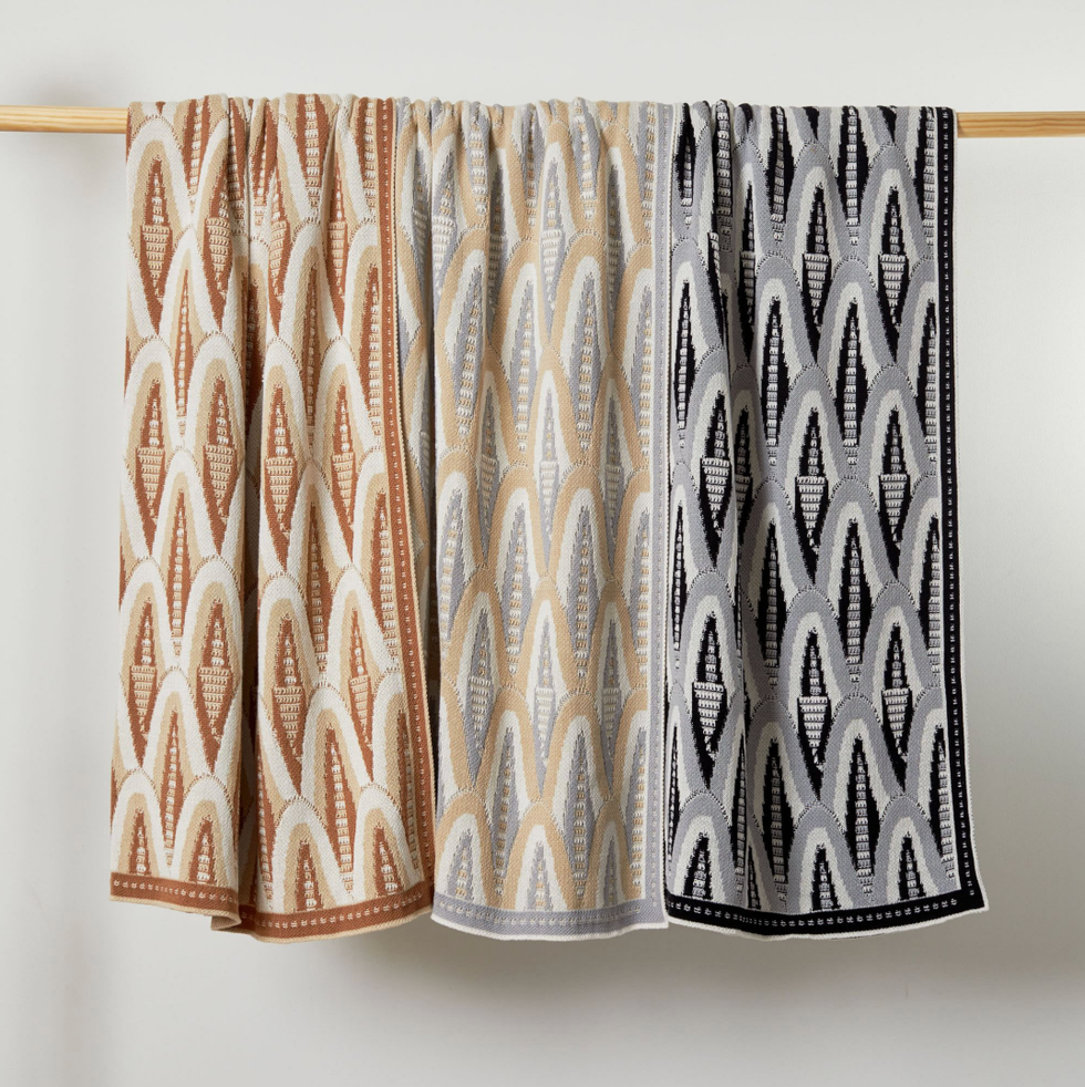 Three patterned towels hanging, featuring brown, beige, and black designs on a wooden bar.