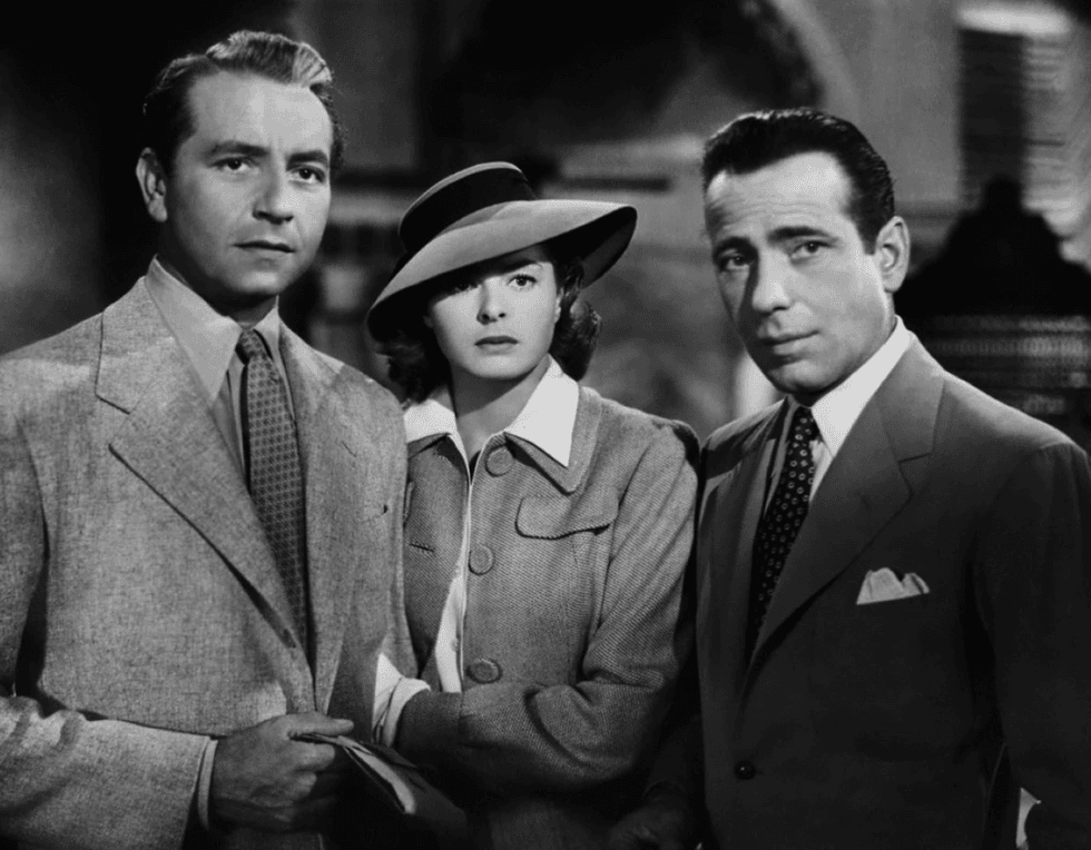 Three people in 1940s attire, with serious expressions, in a black-and-white scene.