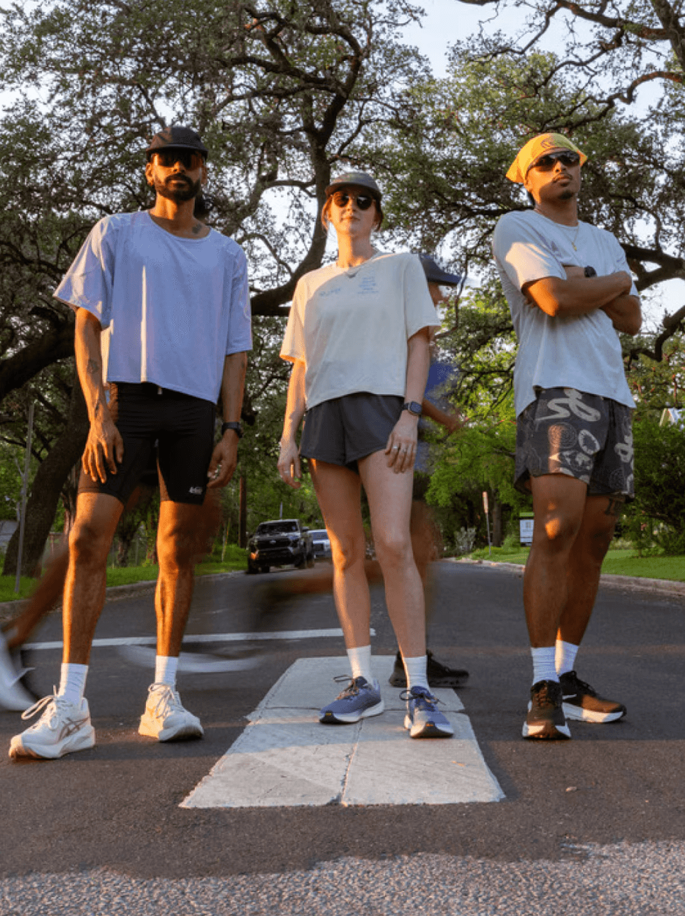 Three people in sporty outfits stand confidently on a crosswalk.