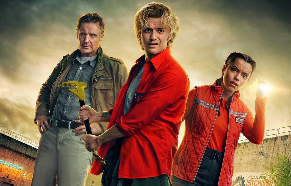 Three people in work uniforms, one holding a tool, stand with a dramatic sky background.