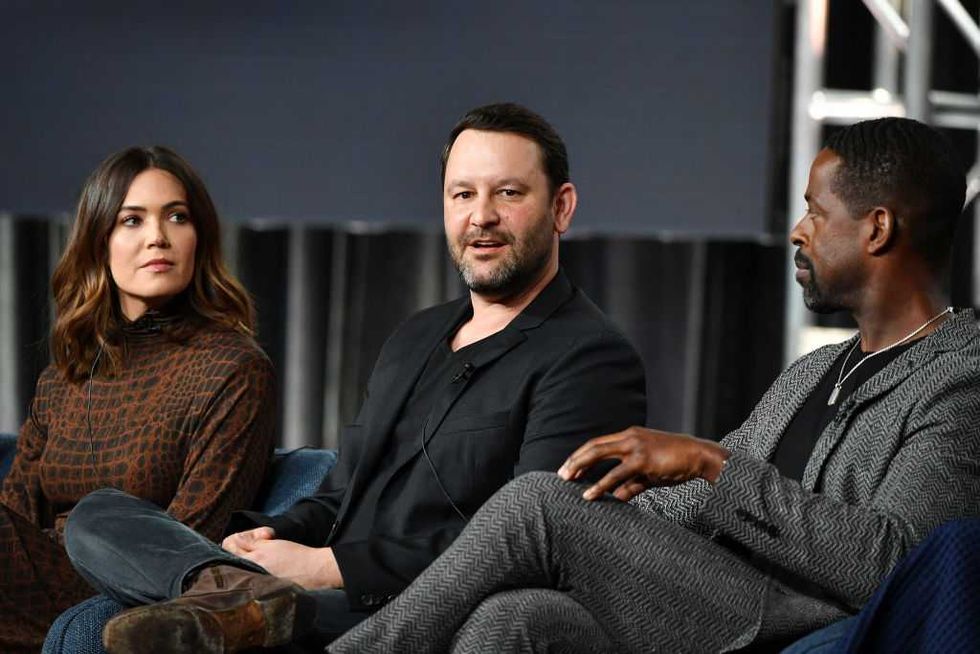 Three people seated, engaged in conversation on a panel discussion stage.