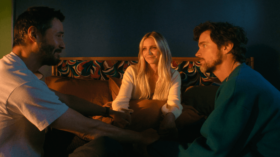 Three people sitting closely, smiling warmly, sharing an intimate moment in soft lighting.