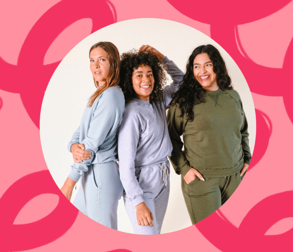 Three people smiling in casual outfits against a pink, abstract background.