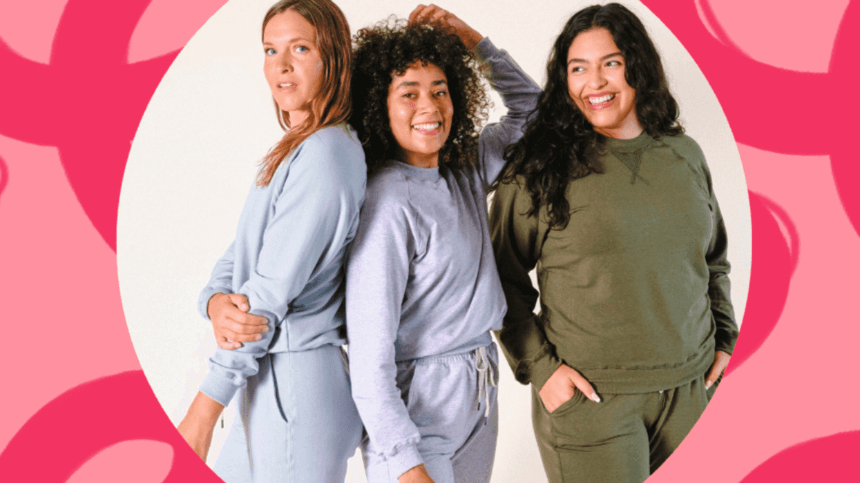 Three people smiling in casual outfits against a pink, abstract background.