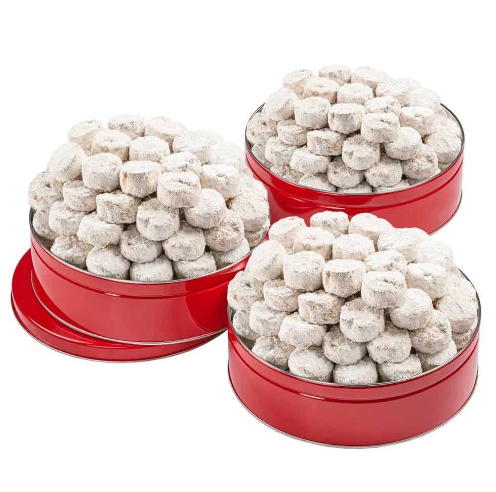 Three red tins filled with powdered sugar-coated cookies.