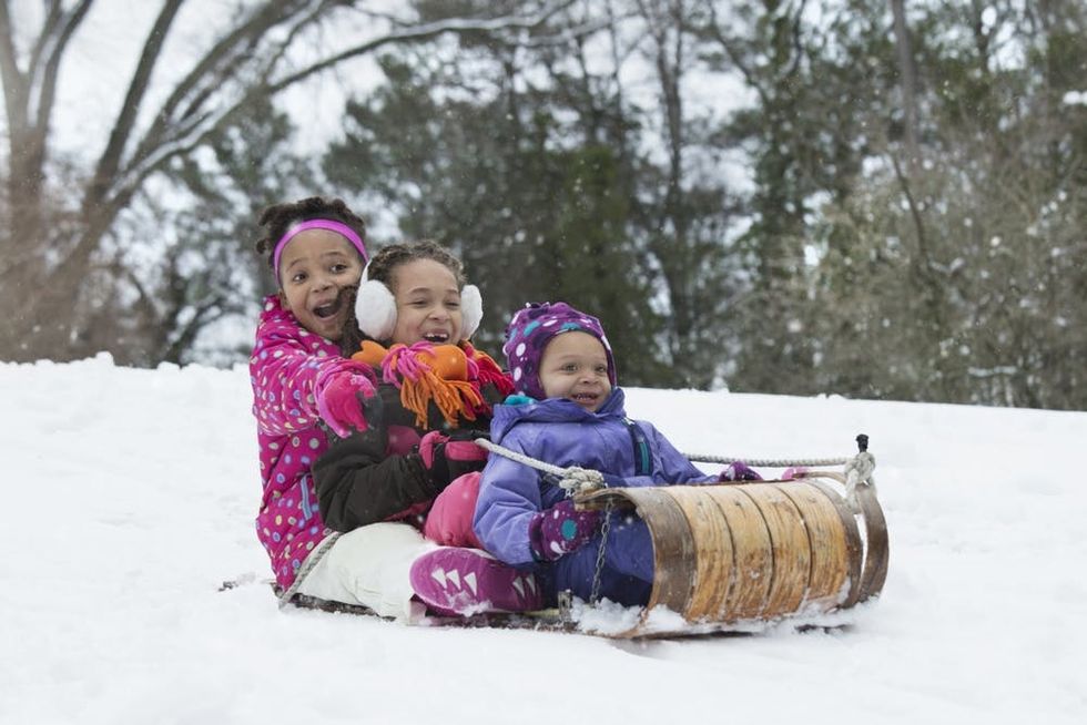 Three sisters sled in the snow
