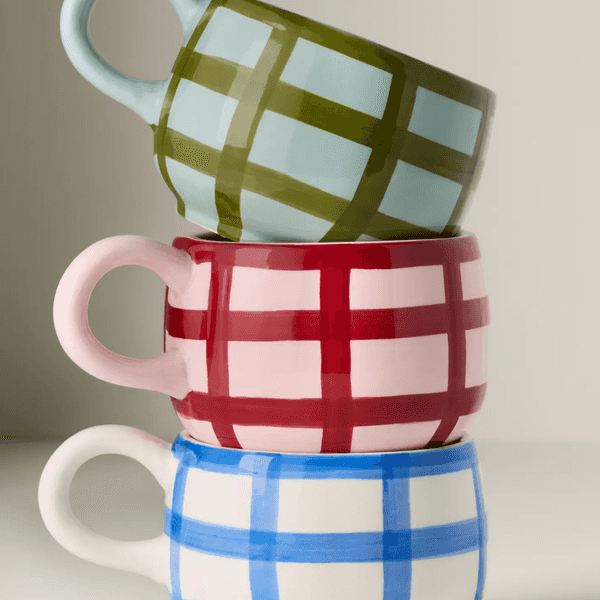 Three stacked mugs with plaid patterns in green, red, and blue.