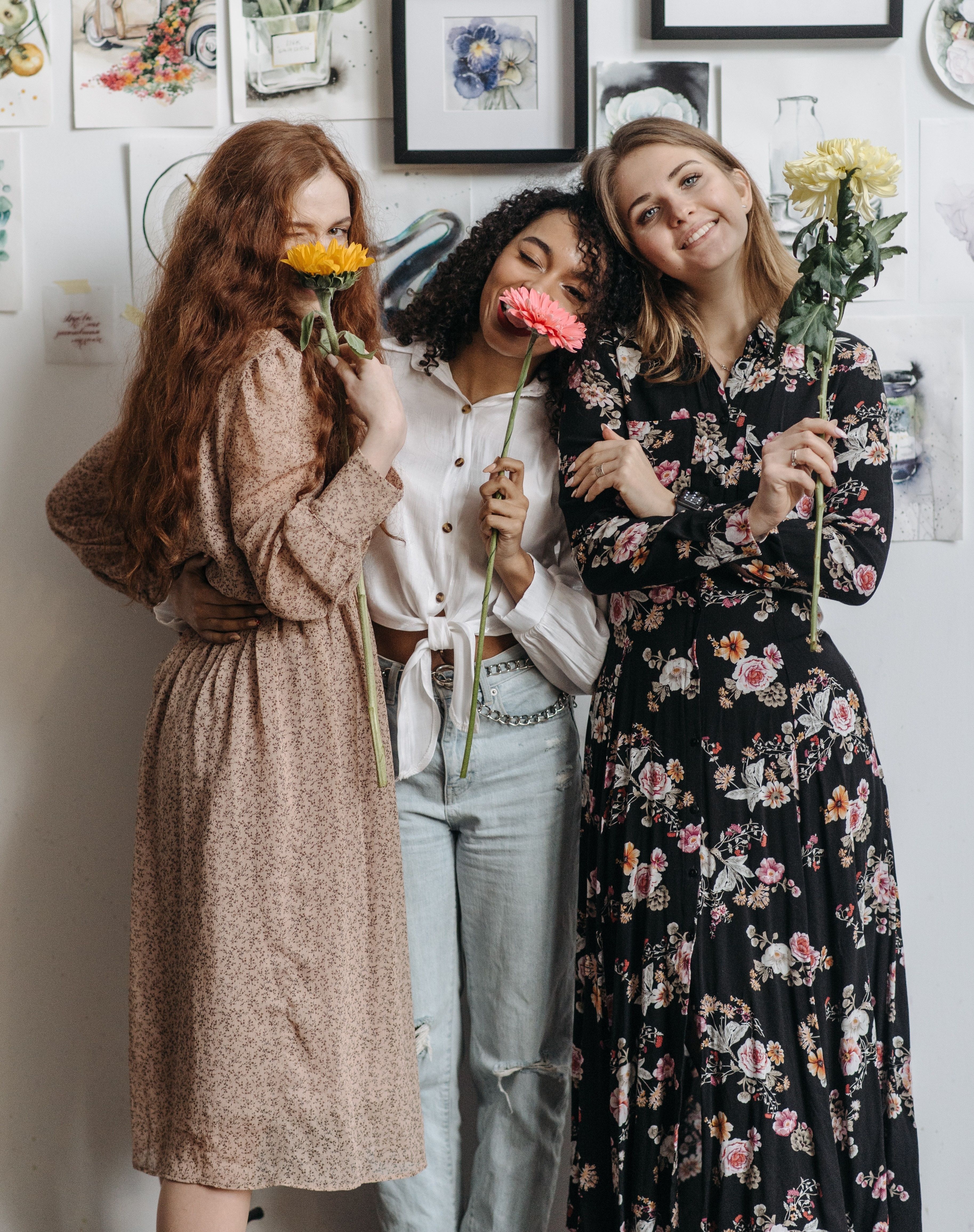 Three women are holding up flowers.