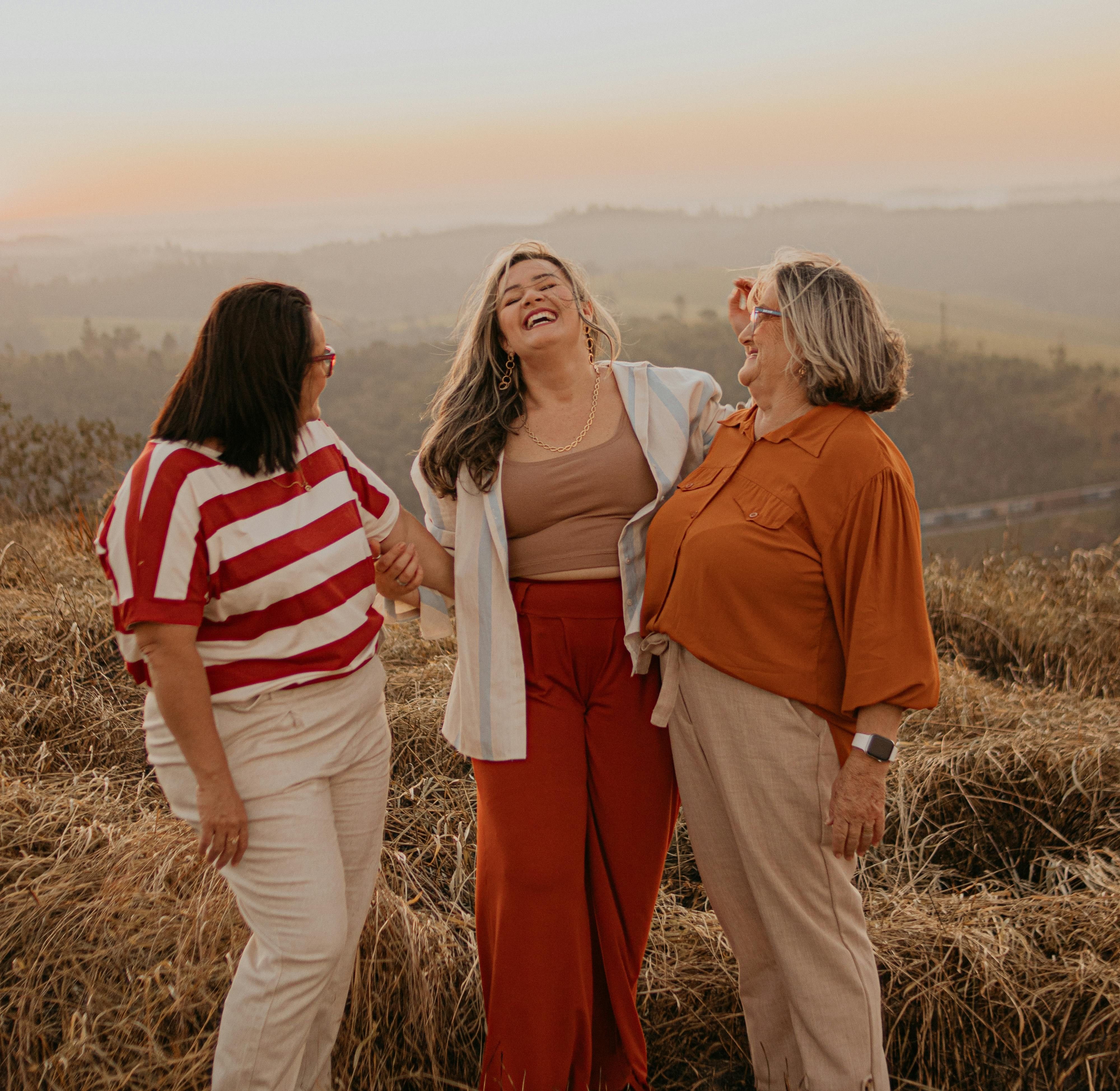 three women laughing together at sunset in the fall