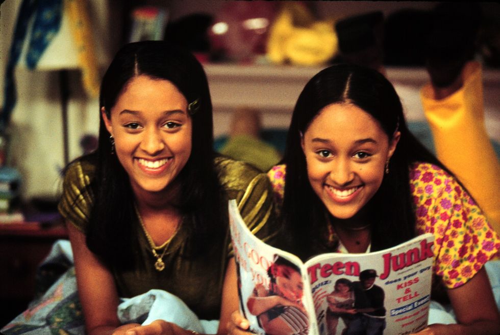 Tia and Tamera are lying down and read a teen magazine.