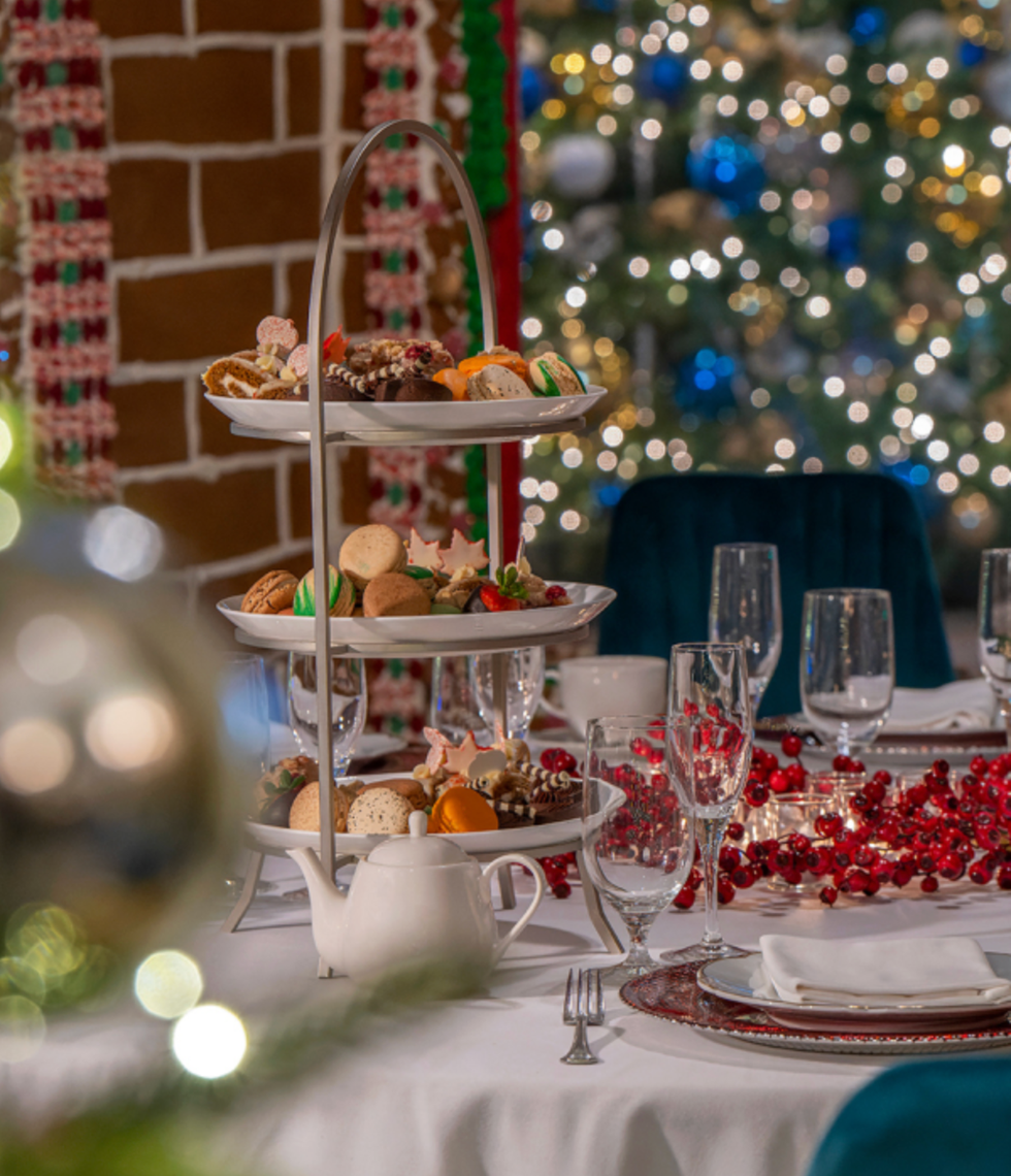 Tiered dessert tray on a festive table with holiday decorations and lights.