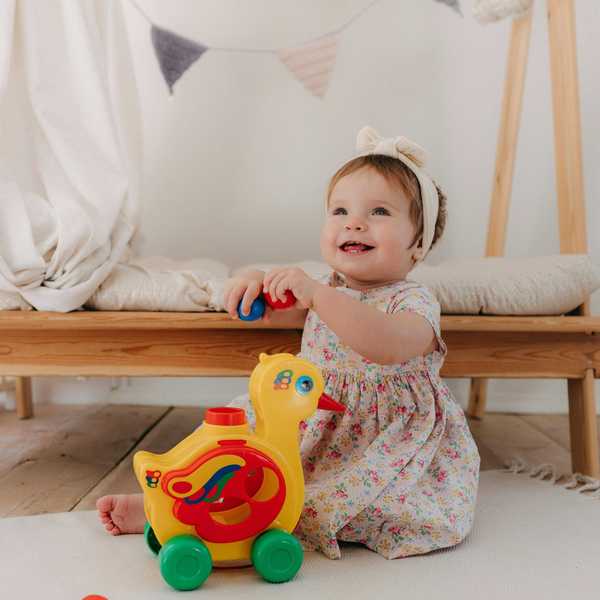 Toddler playing with colorful blocks and a toy duck in a cozy room.