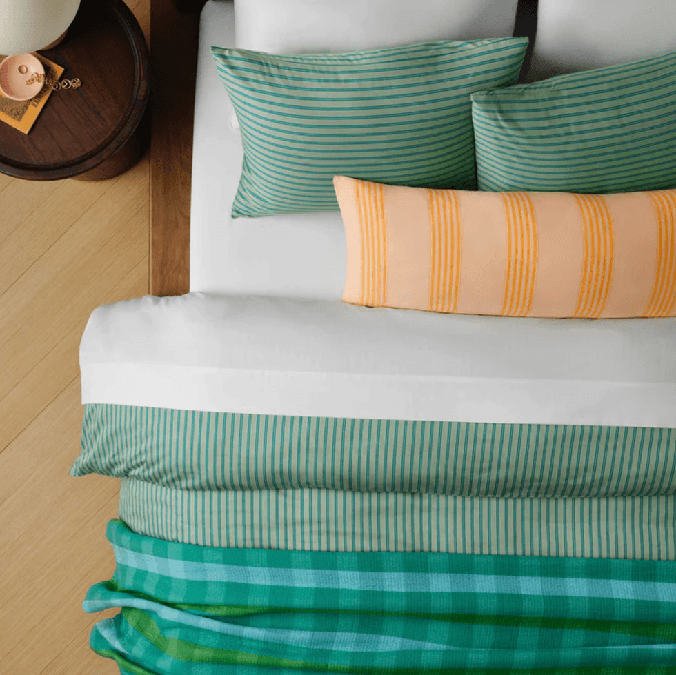 Top view of a neatly made bed with striped pillows and a plaid blanket.