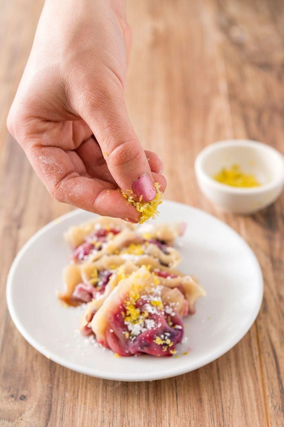 topping the fruit with powdered sugar and lemon zest