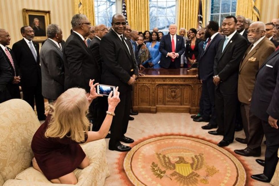 TOPSHOT - Counselor to the President Kellyanne Conway takes a photo as US President Donald Trump and leaders of historically black universities and colleges talk before a group photo in the Oval Office of the White House before a meeting with US Vice President Mike Pence February 27, 2017 in Washington, DC. / AFP / Brendan Smialowski (Photo credit should read BRENDAN SMIALOWSKI/AFP/Getty Images)