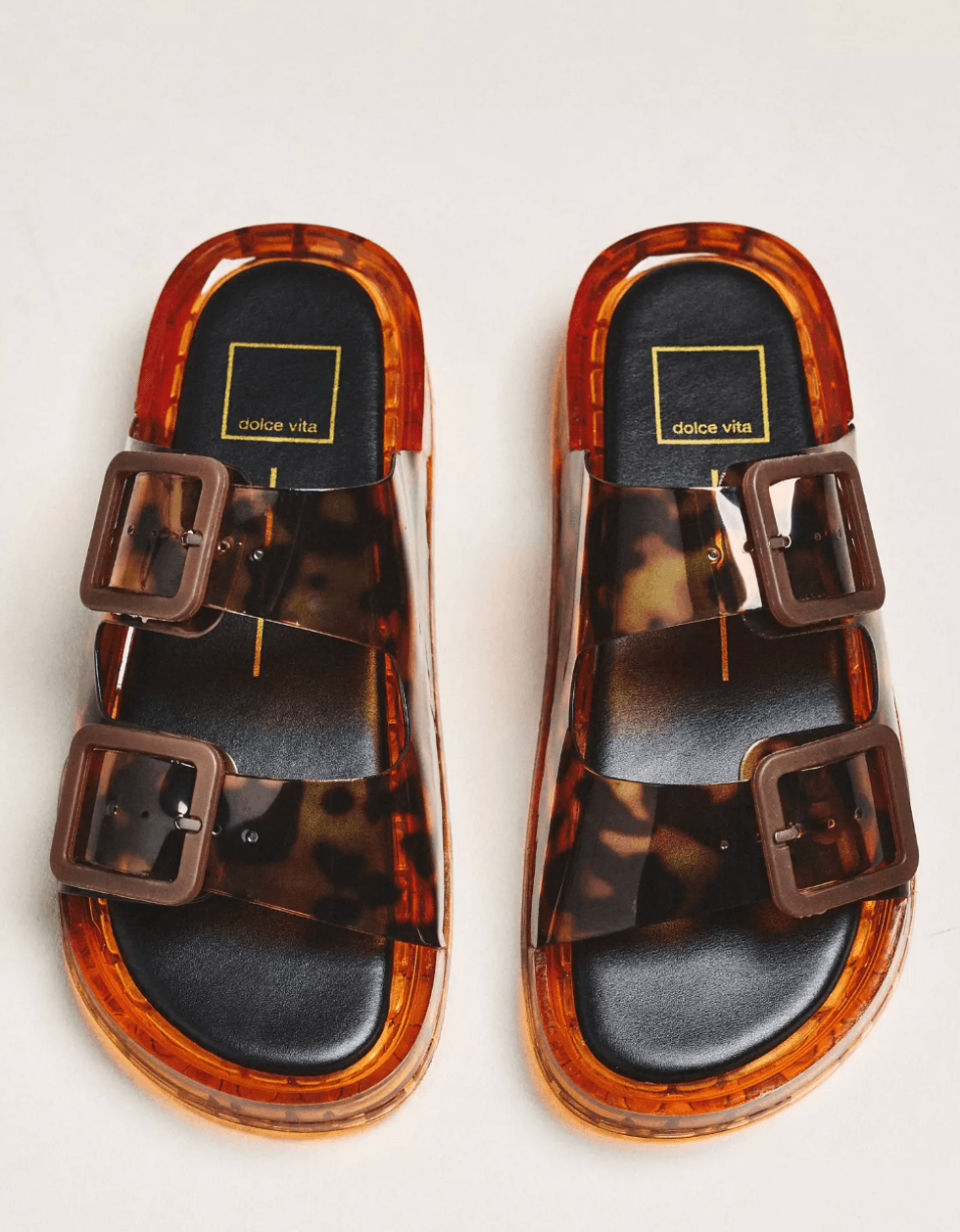 Tortoiseshell-pattern sandals with double buckles and transparent amber soles.