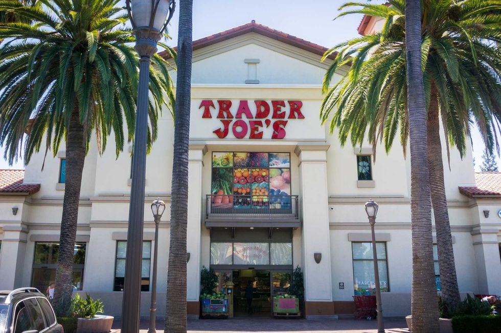 Trader Joe's store entrance flanked by tall palm trees on a sunny day.