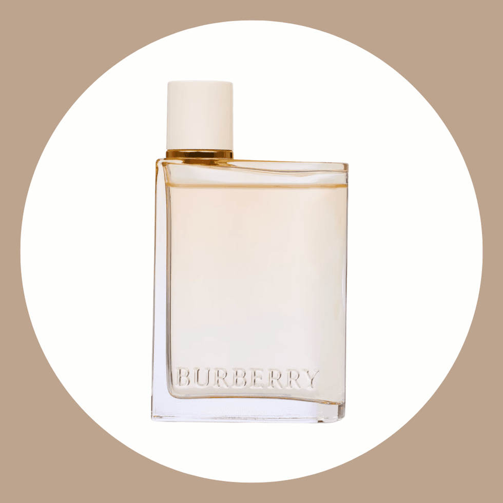 Transparent perfume bottle with "Burberry" logo, white cap, beige background.