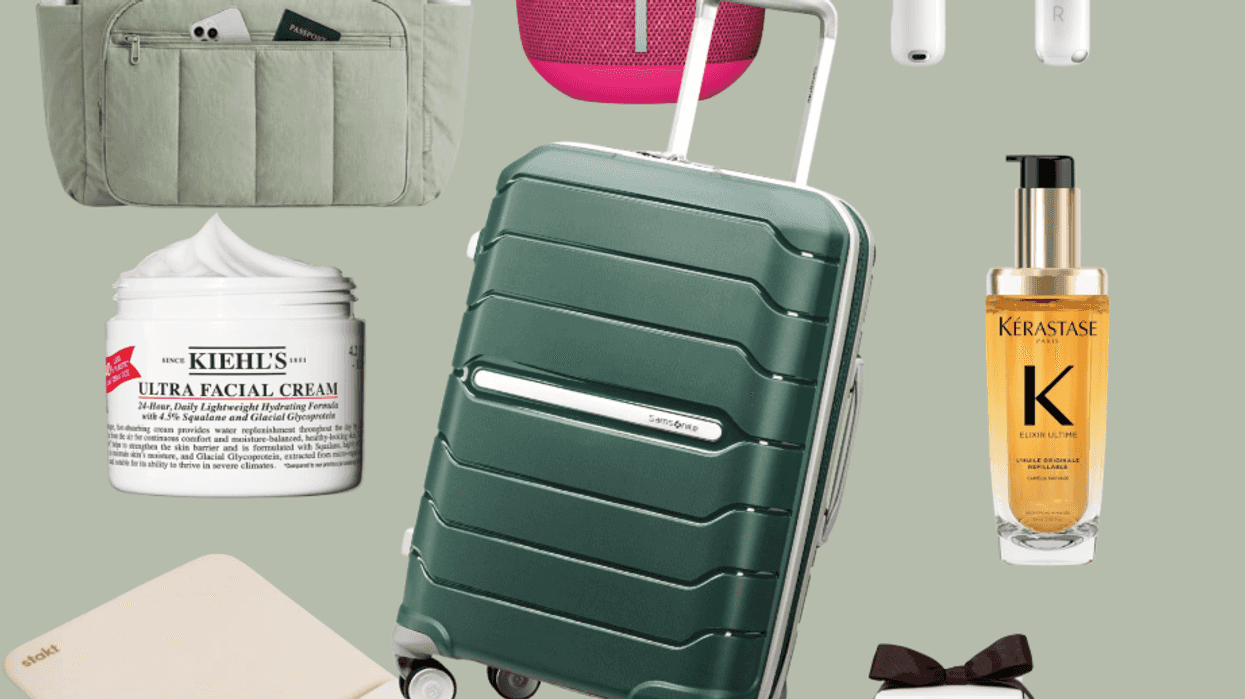 Travel essentials: suitcase, tote, speaker, earbuds, cream, oil, notebook, candle set.
