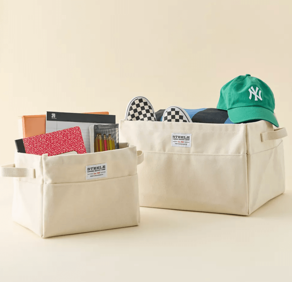 Two beige storage bins with school supplies, sneakers, and a green cap.