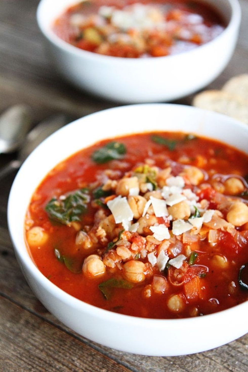Two bowls of chickpea ferro soup sit on a wooden table.