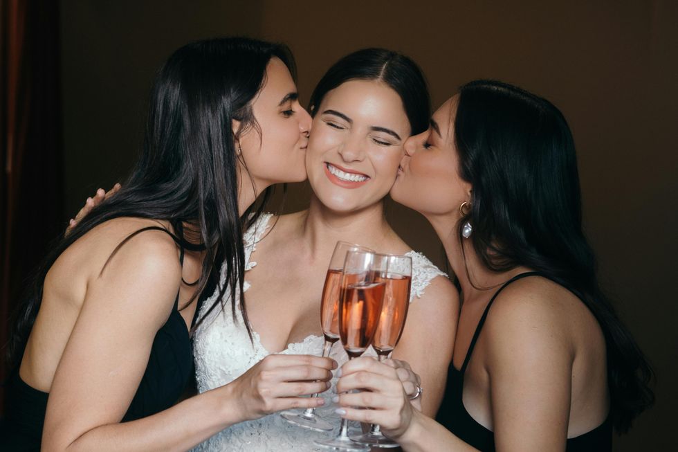 two bridesmaids kissing the bride on the cheek