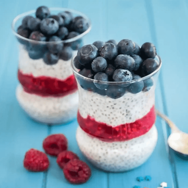 Two chia pudding cups with raspberries and blueberries.