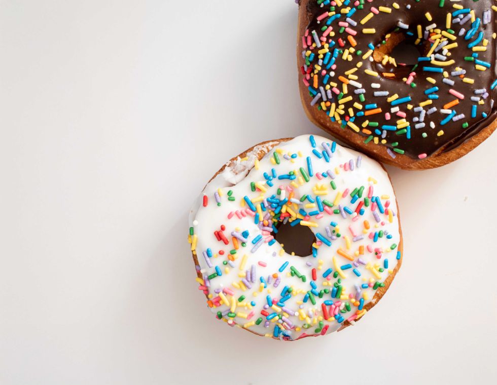Two donuts with sprinkles; one chocolate, one vanilla.