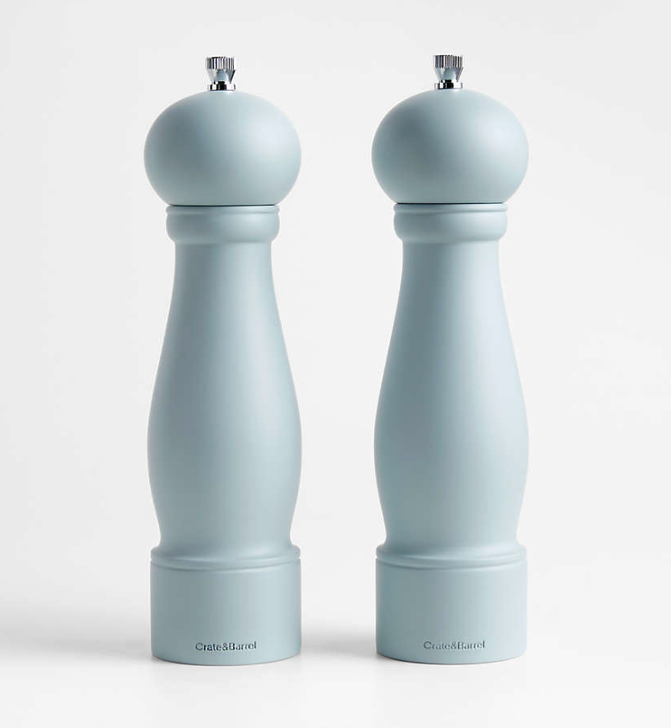 Two elegant light blue pepper mills with chrome knobs on a white background.