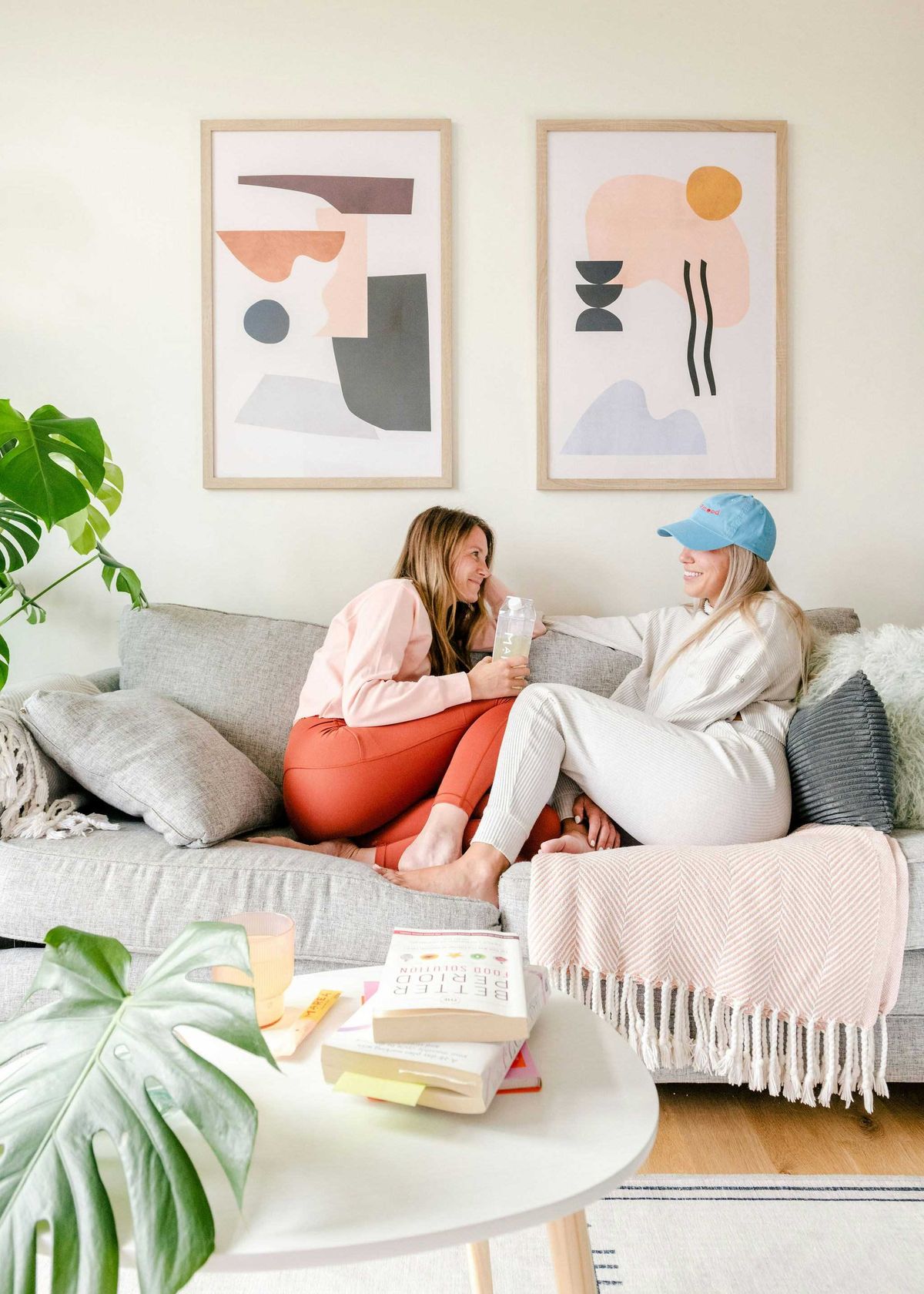 Two friends chatting on a cozy sofa in a bright, modern living room.