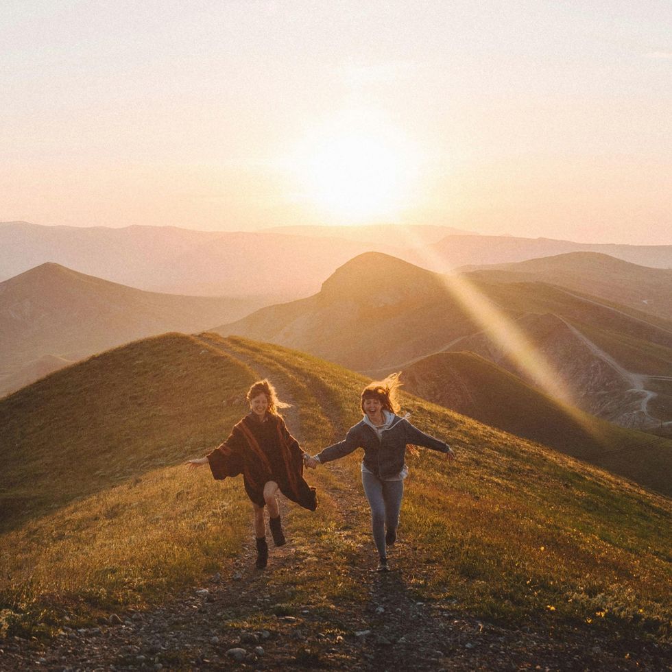 two friends running on a mountain path at sunset