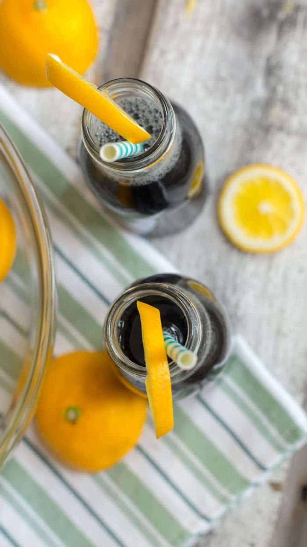 Two glasses of Black Charocal Lemonade are sitting on a striped towel.