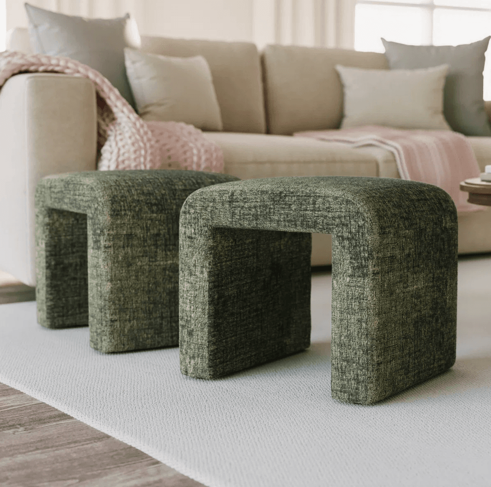 Two green ottomans on a white rug in front of a beige sofa with pillows and a throw.