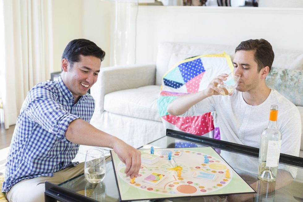 two guys playing a board game drinking wine