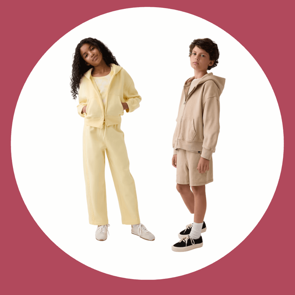 Two kids in casual hoodies, one yellow and one beige, on a circular maroon background.