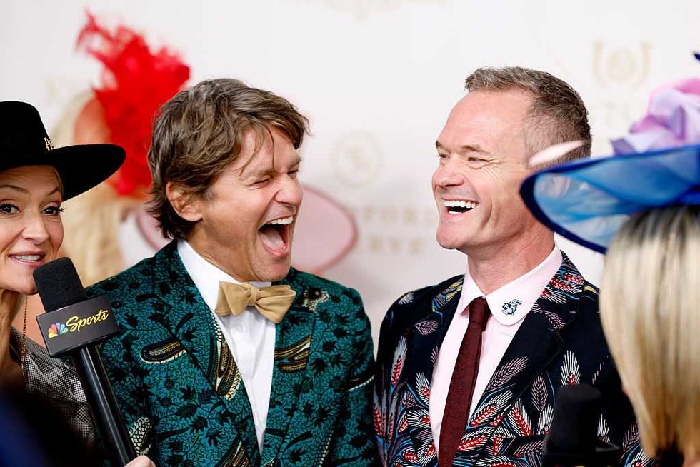 Two men in vibrant suits laughing during an NBC Sports interview.