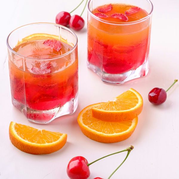 two orange and cherry drink in glasses
