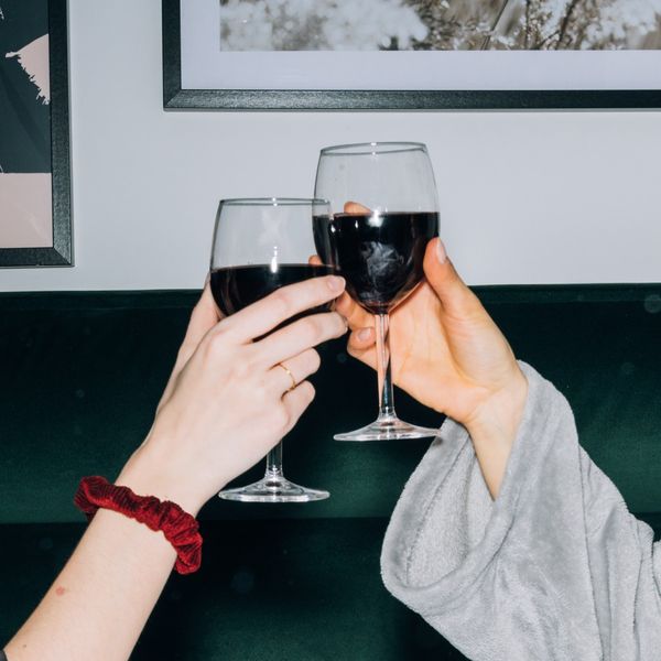 two people cheersing glasses of red wine