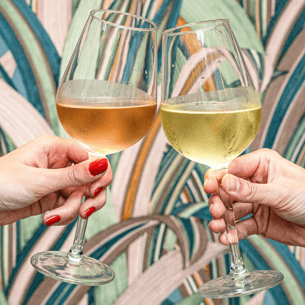 Two people clinking white wine glasses against a colorful abstract wallpaper.