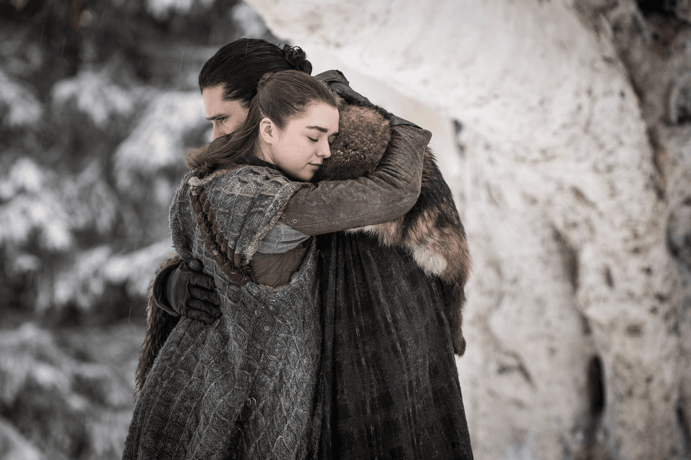 Two people embrace warmly in a snowy, forested setting.