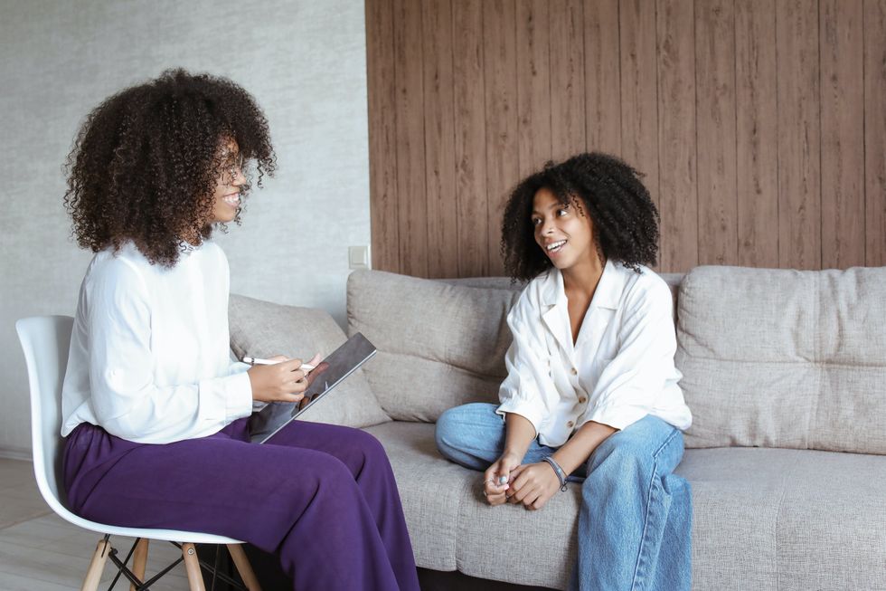 Two people having a friendly conversation on a couch, one with a tablet.