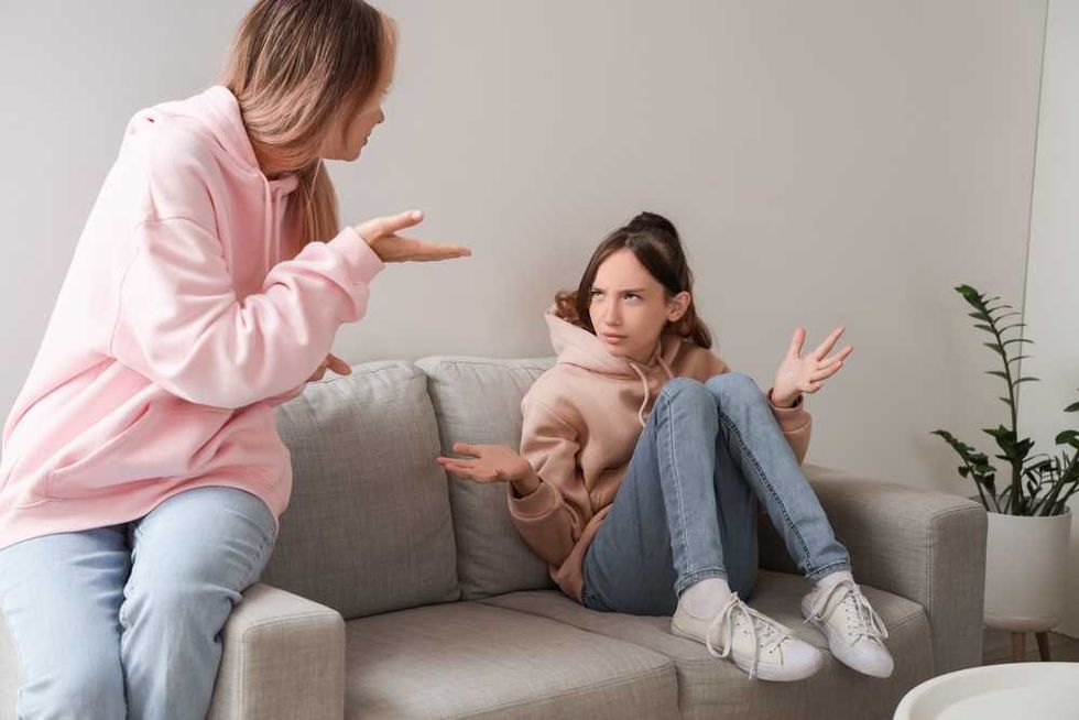 Two people in hoodies having a heated discussion on a couch.