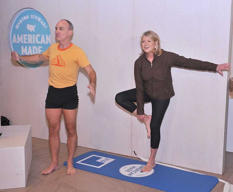 Two people practicing yoga poses on mats indoors.