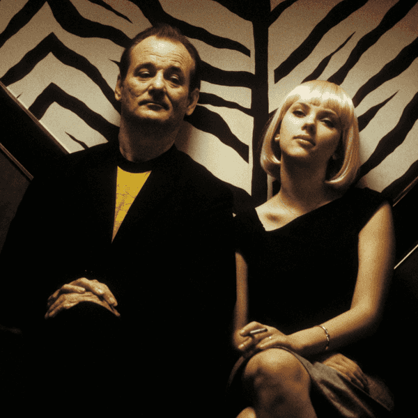 Two people seated against a zebra-patterned wall, looking contemplative.