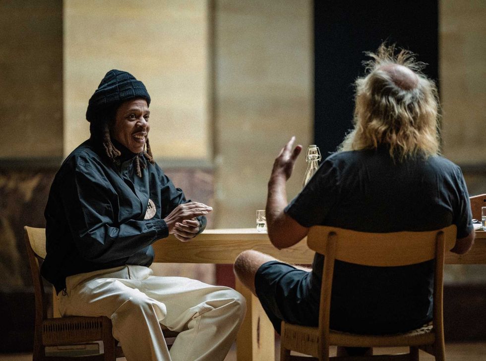 Two people sitting at a table having a lively conversation indoors.