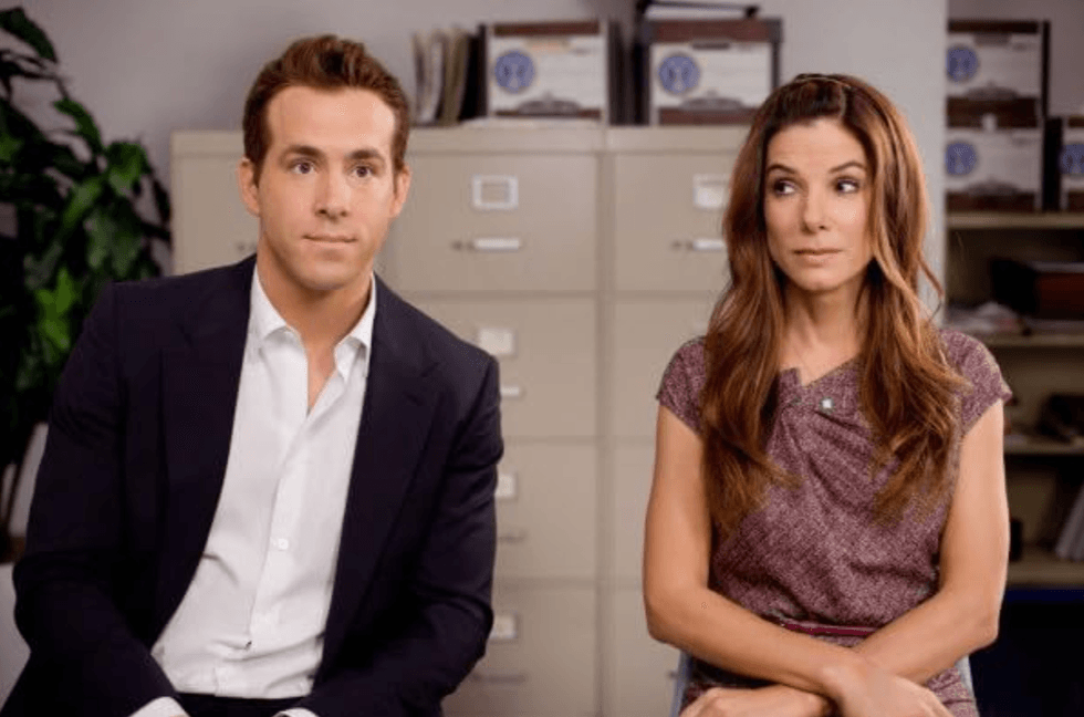 Two people sitting in an office, looking to the side with a curious expression.