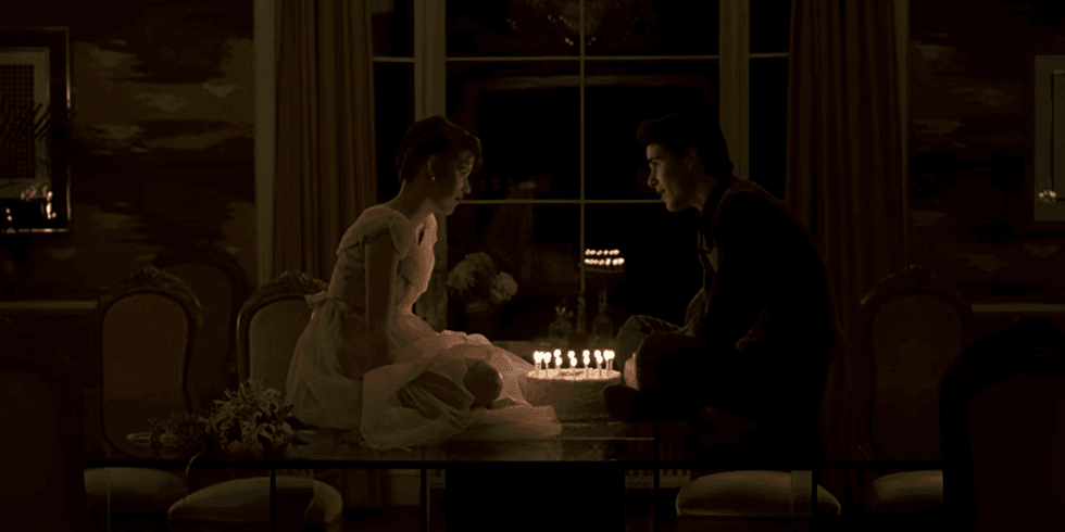 Two people sitting on a table lit by candles in a dimly lit room.