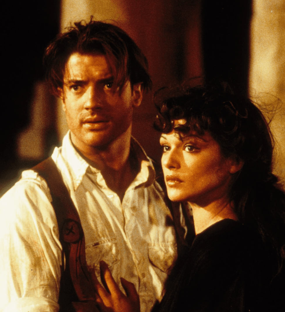 Two people stand close, looking determined, in a dramatic, warm-lit scene.
